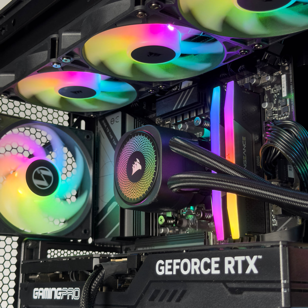 Close-up of a high-performance PC build featuring multiple RGB LED fans, a Corsair liquid CPU cooler, a RAM module, and a GeForce RTX graphics card inside a desktop case.